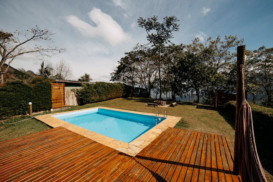 Adelaide swimming pool with travertine surround, glass fencing and tropical-look planting